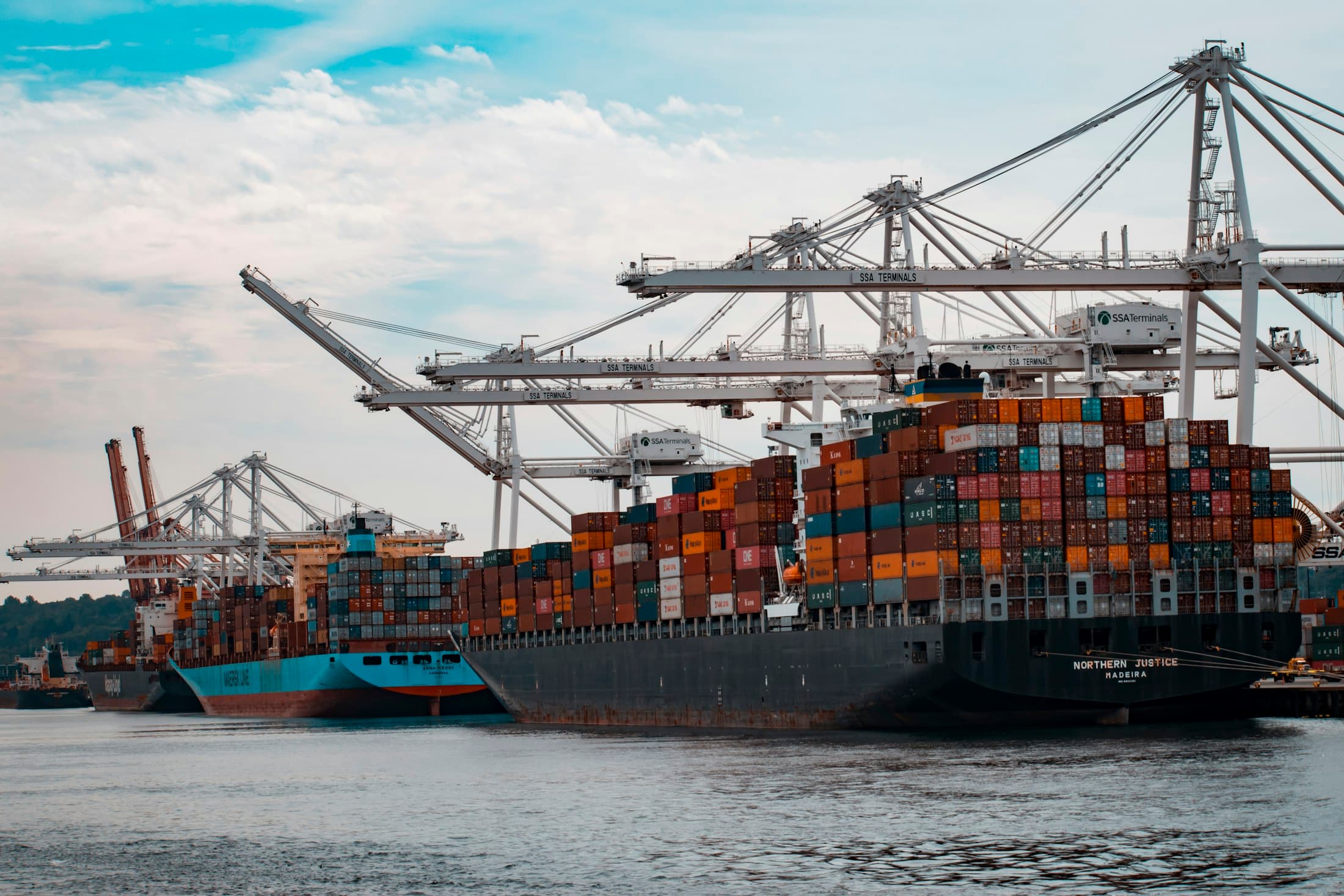 Container vessel alongside gantry cranes at a deep-water port at dusk